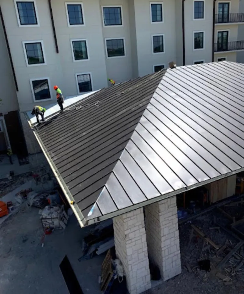 Crew installing standing seam metal roof panels on a commercial project in West Pennsboro